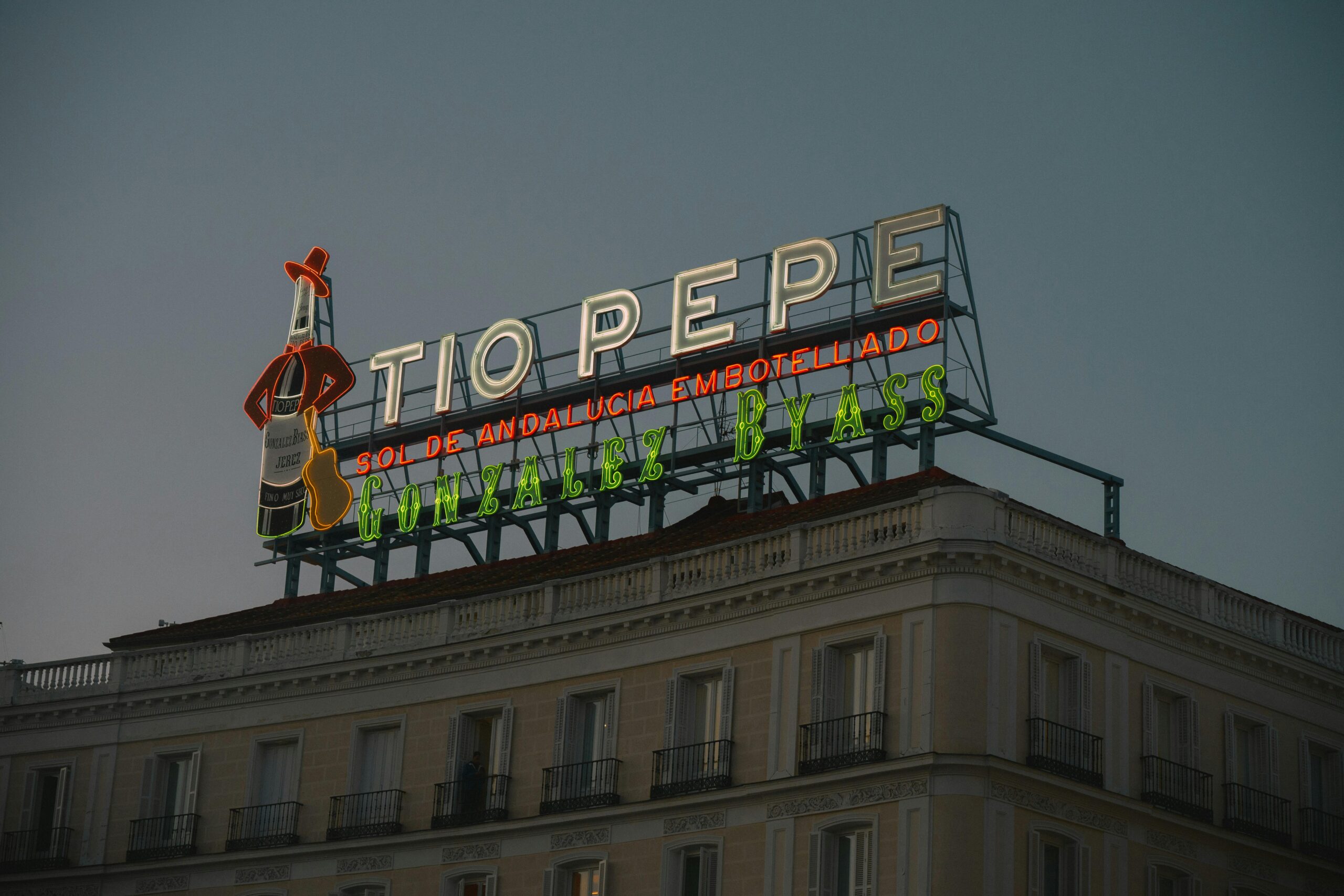 Neon Tio Pepe sign glowing at dusk in downtown Madrid's Puerta del Sol.